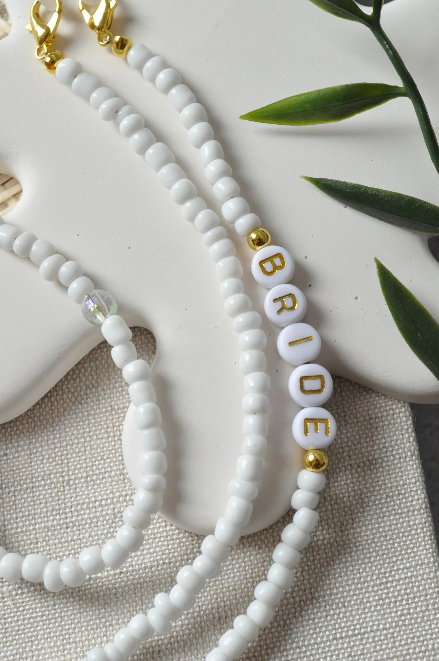 Close-up of the beaded glasses chain featuring the "Bride" inscription, highlighting the intricate detailing of the letters against off-white background.