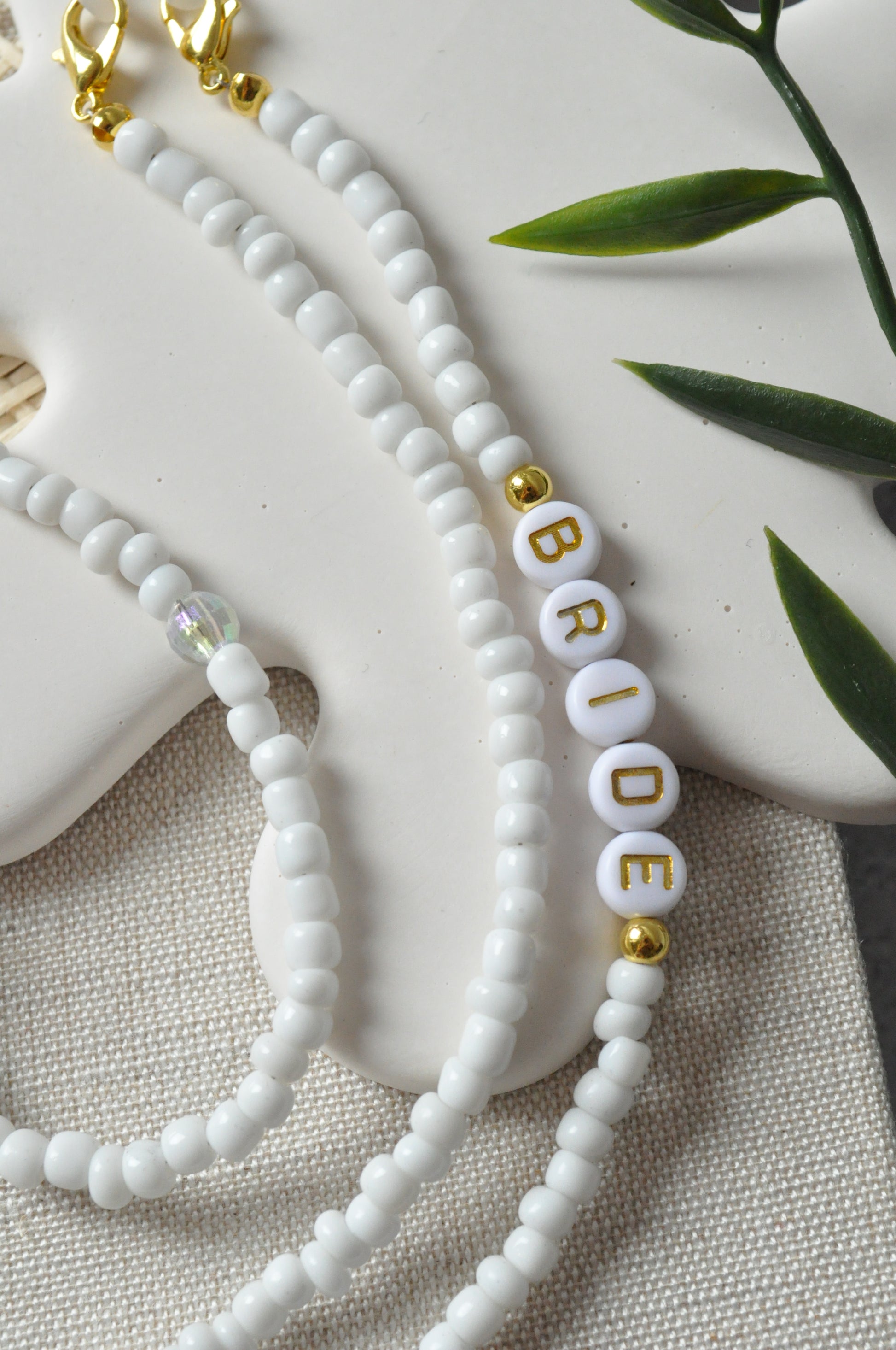Close-up of the beaded glasses chain featuring the "Bride" inscription, highlighting the intricate detailing of the letters against off-white background.