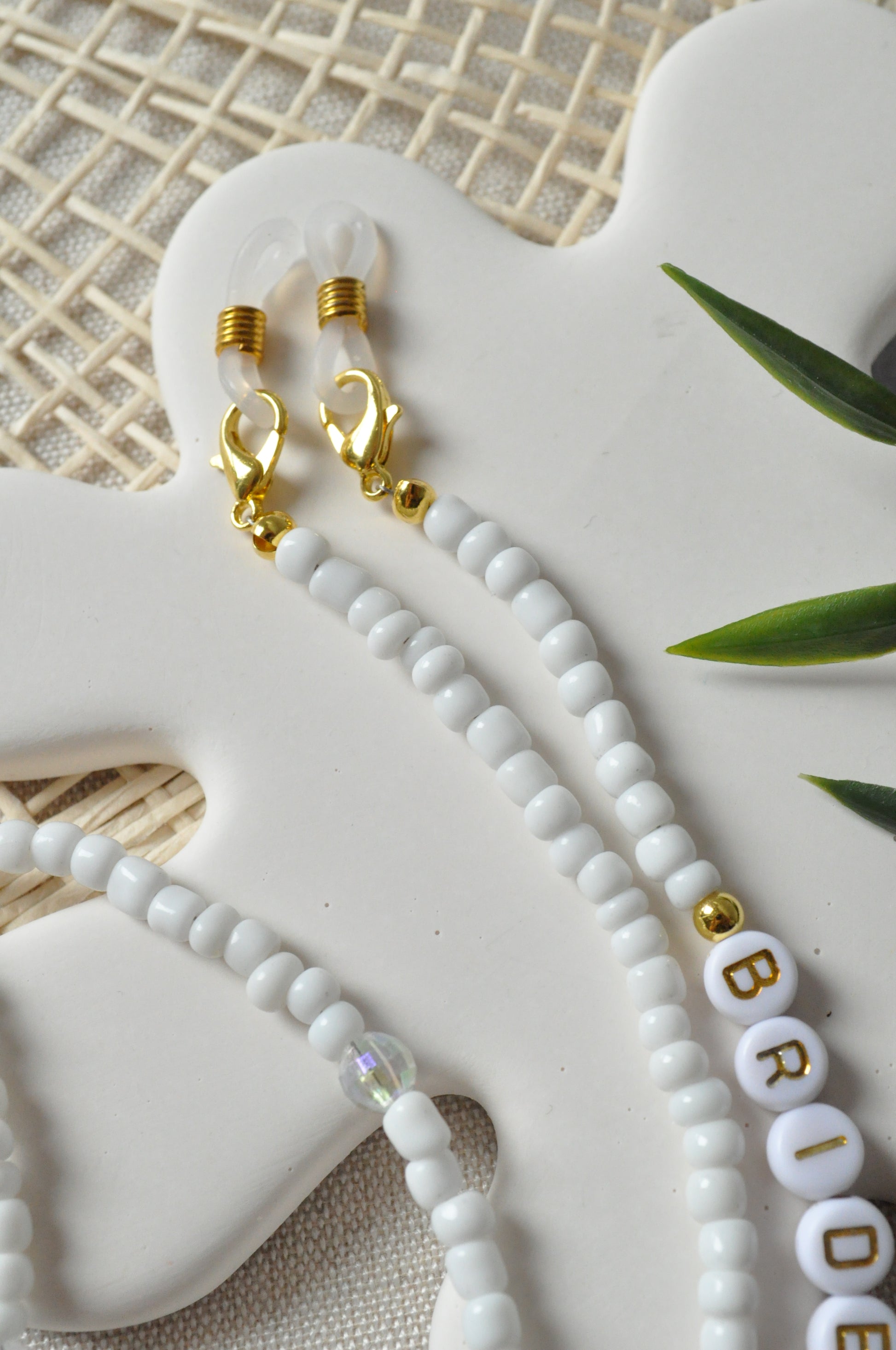 Close-up of the beaded glasses chain, showcasing the gold-detailed rubber holders and clasps against an off-white background.
