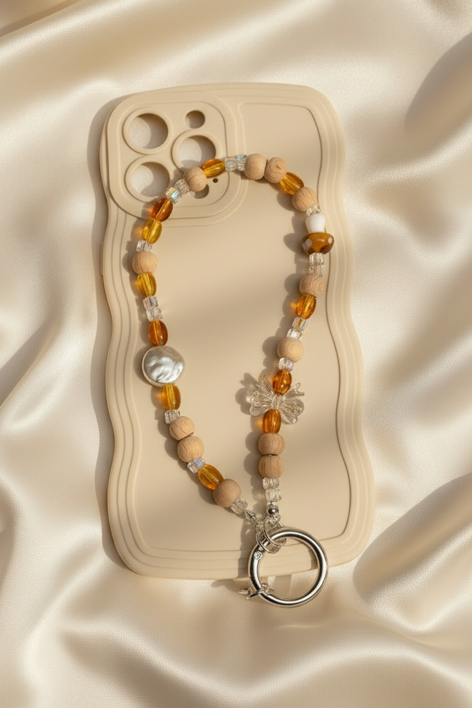 Beaded phone charm with a keyring on a beige card against a beige fabric background