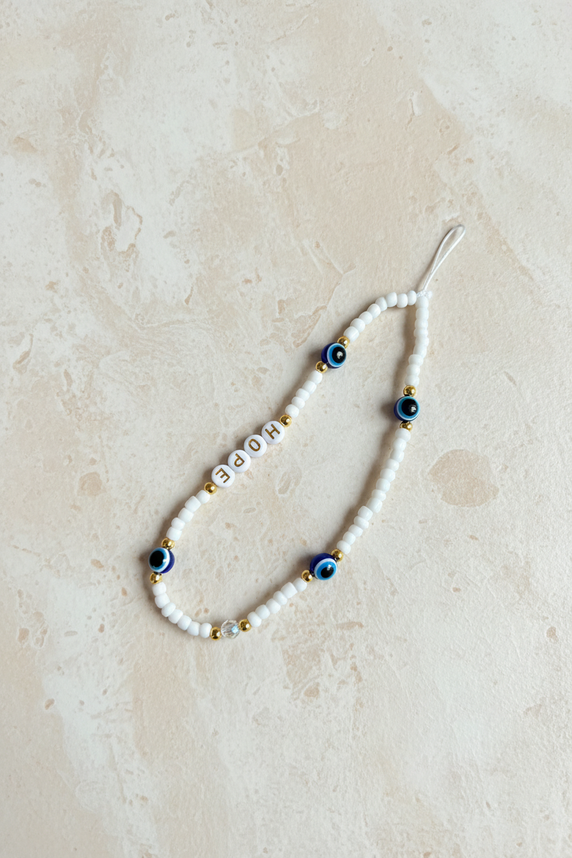 Pearl necklace with blue and gold accents on a beige surface