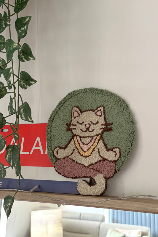 Round rug with a cat design on a shelf next to a plant