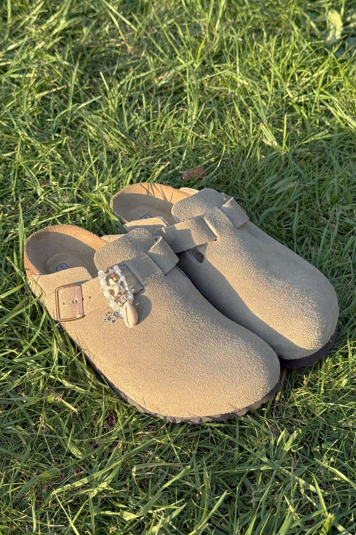 Pair of beige clogs with a bow on grass