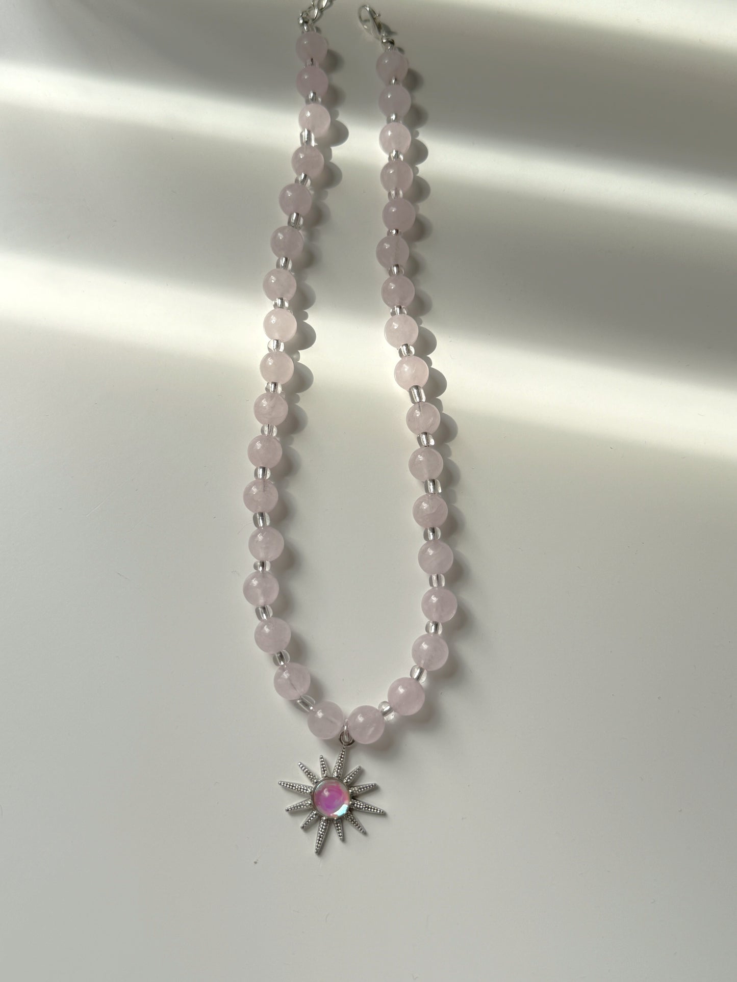 Necklace with pink beads and a star-shaped pendant on a white background
