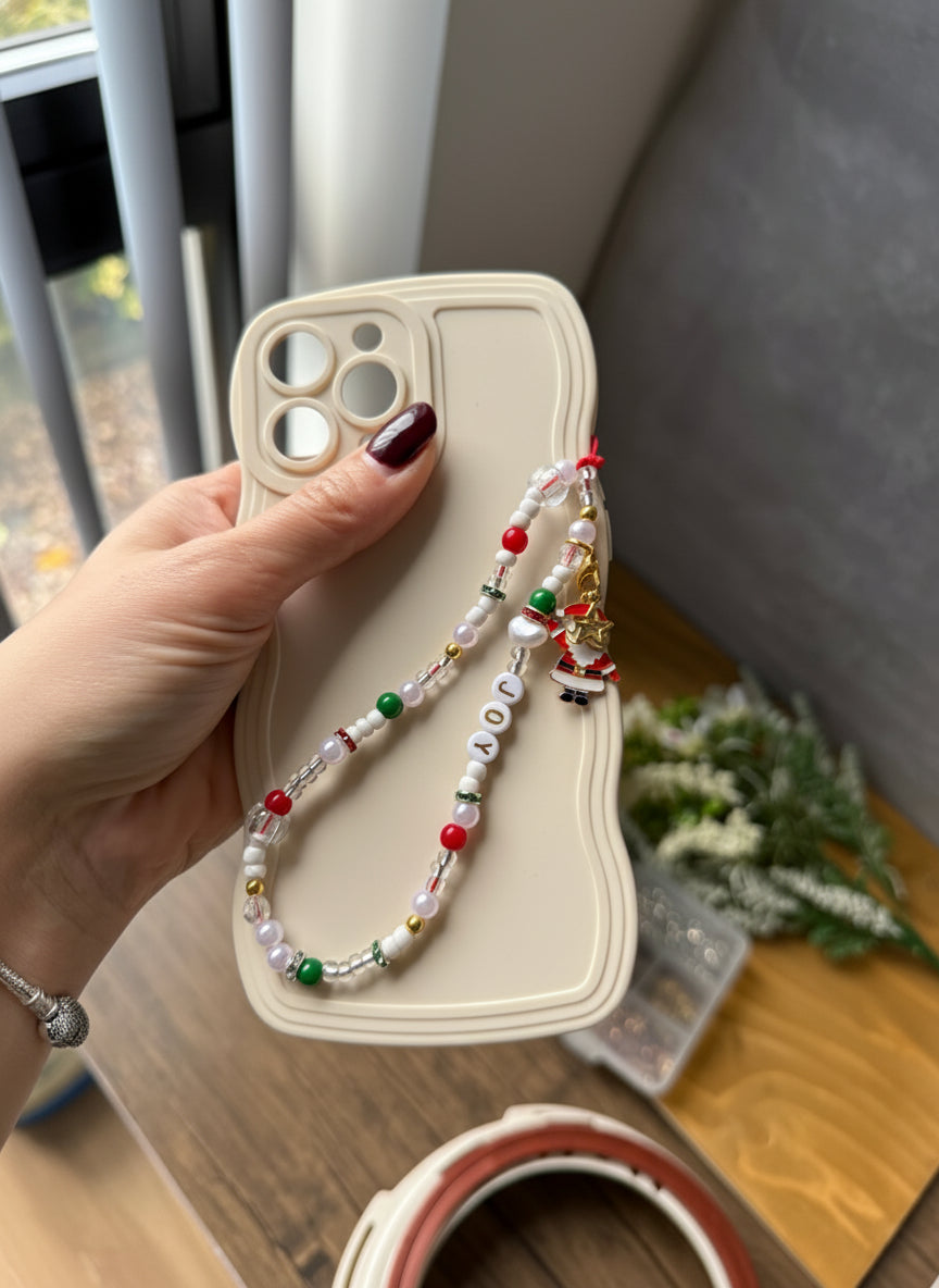 Phone case with a decorative string held by a hand on a wooden surface.