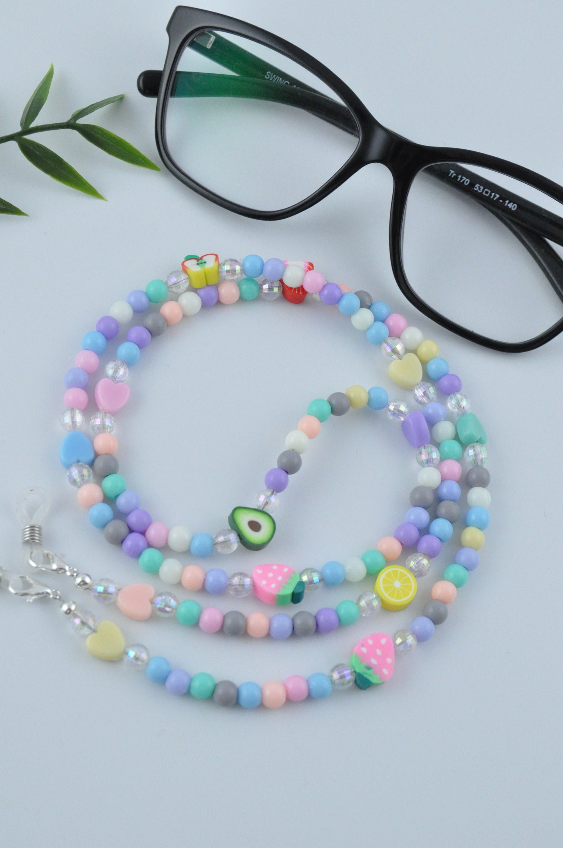 Fruit Salad Pastel Beaded Glasses Chain displayed with reading glasses on a grey background.